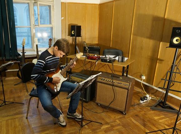 студент, берущий уроки игры на электрогитаре в рок-академии